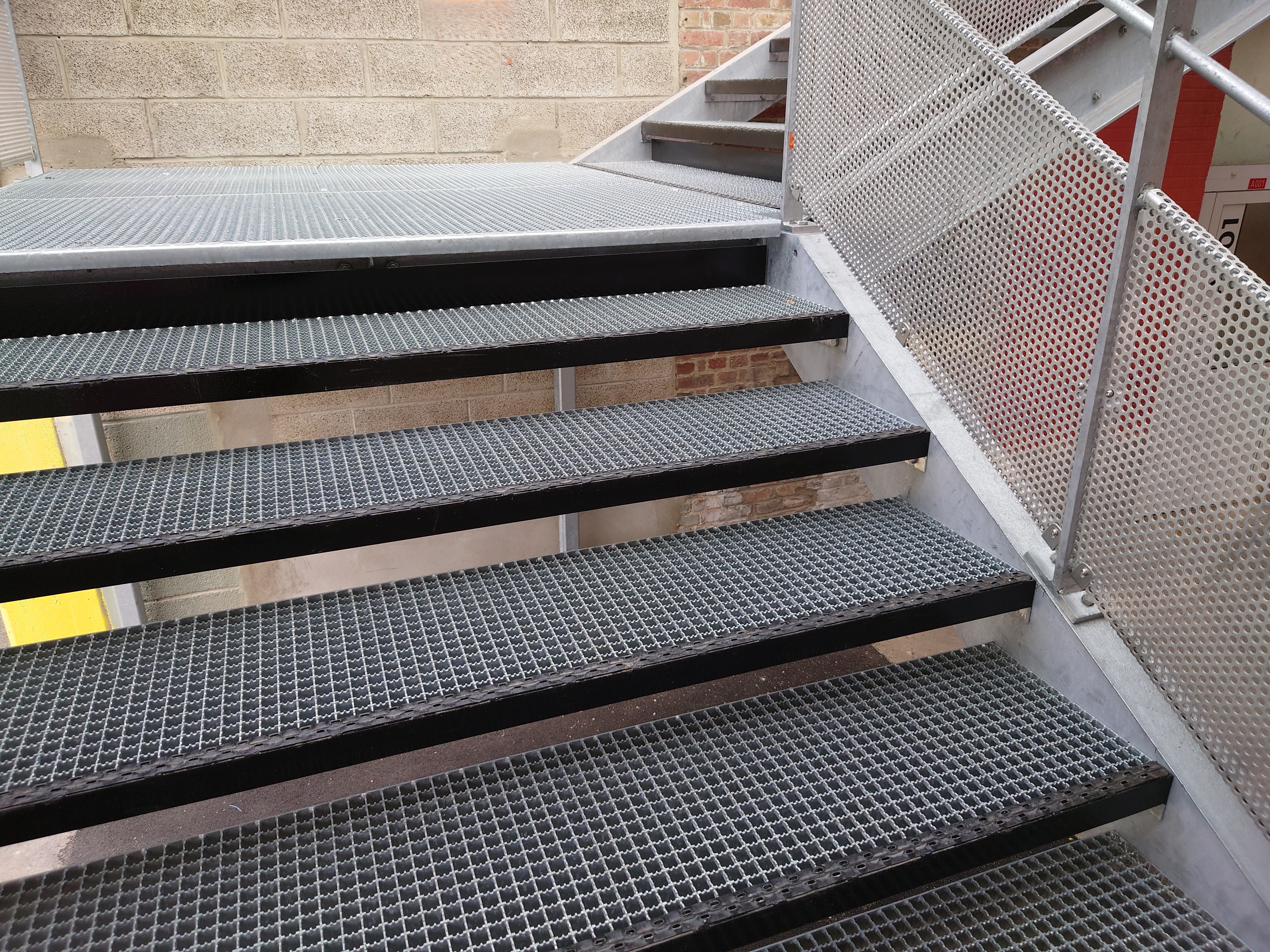 Escalier avec marches en caillebotis pressé avec nez peint et crantage double.